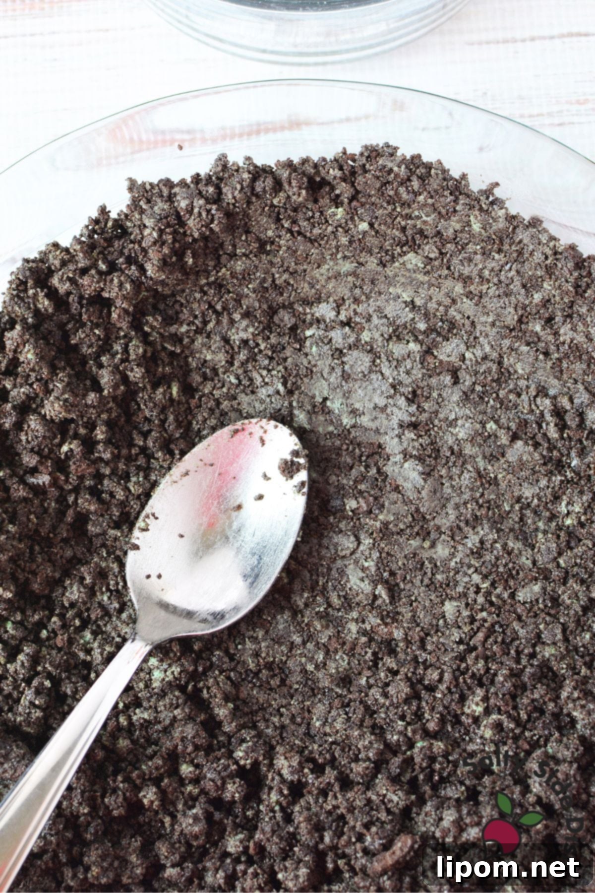 Close-up shot of crushed mint Oreo cookie crumbs mixed with melted butter, ready to be pressed into a pie crust for Grasshopper Pie.