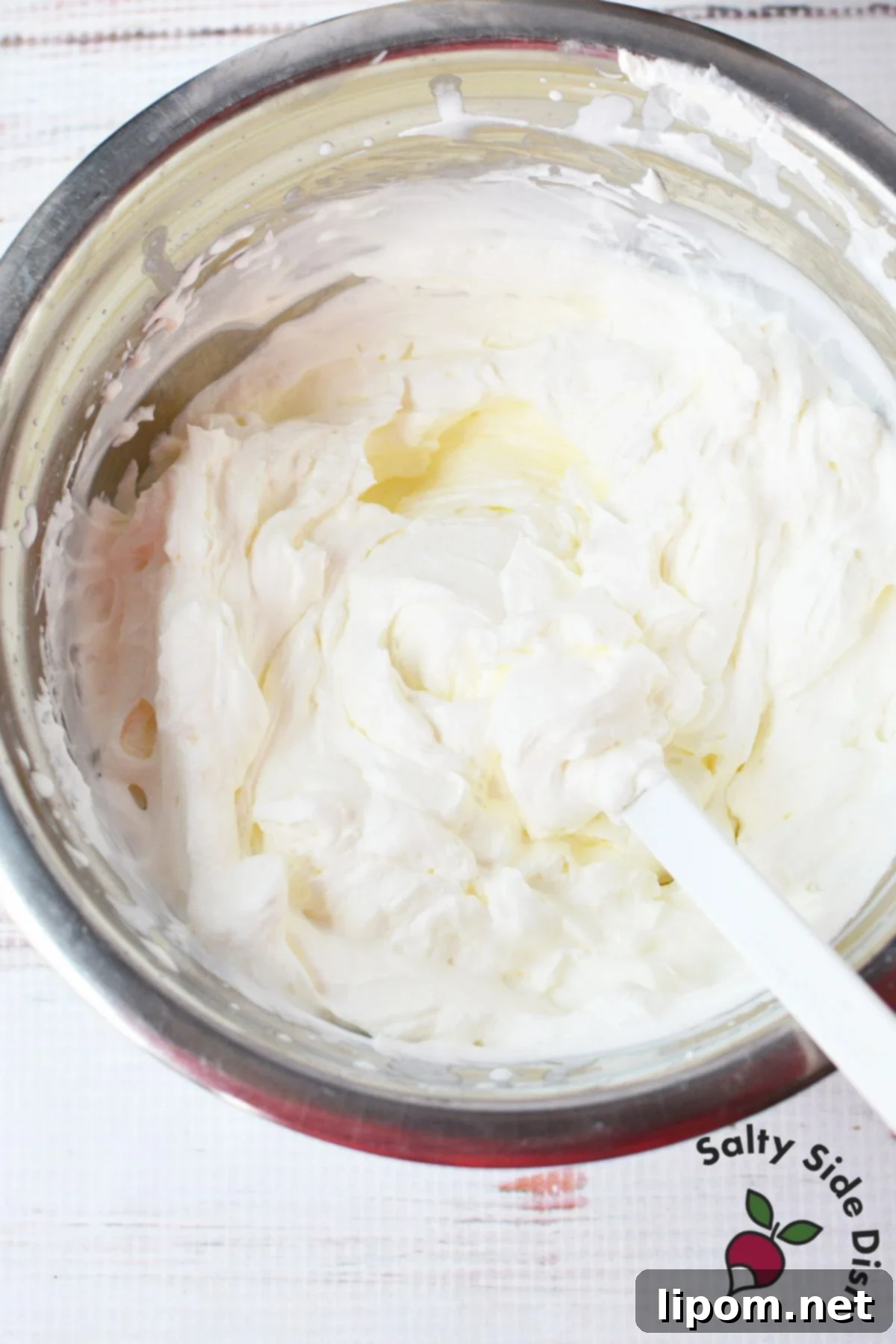 A bowl of thick, mint-green cream cheese mixture, blended smoothly with powdered sugar and peppermint extract, forms the base for the Grasshopper Pie filling.