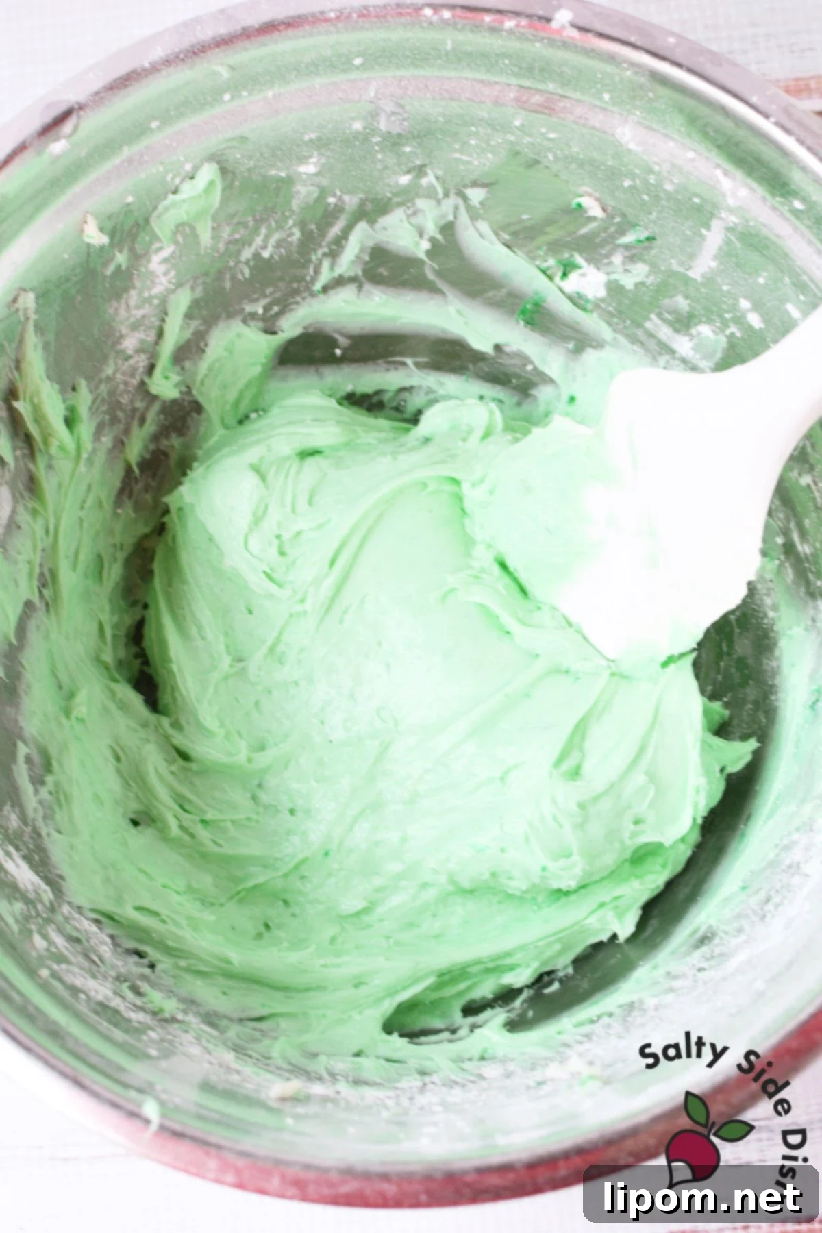 A smooth, light green cream cheese and mint mixture in a mixing bowl, ready to be spread into the pie crust, highlighting its creamy texture.