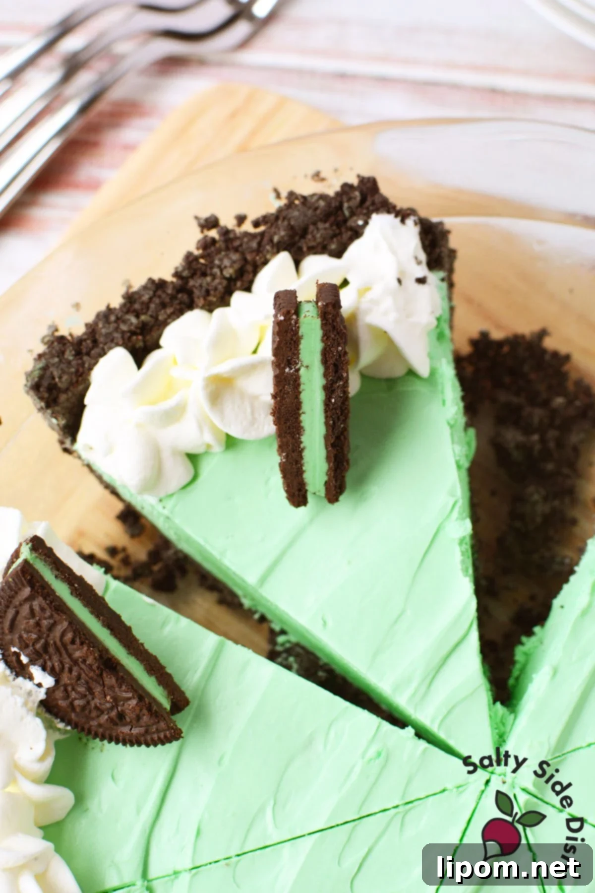 Multiple generous slices of vibrant green Grasshopper Pie neatly arranged in a clear glass pie dish, ready for serving.