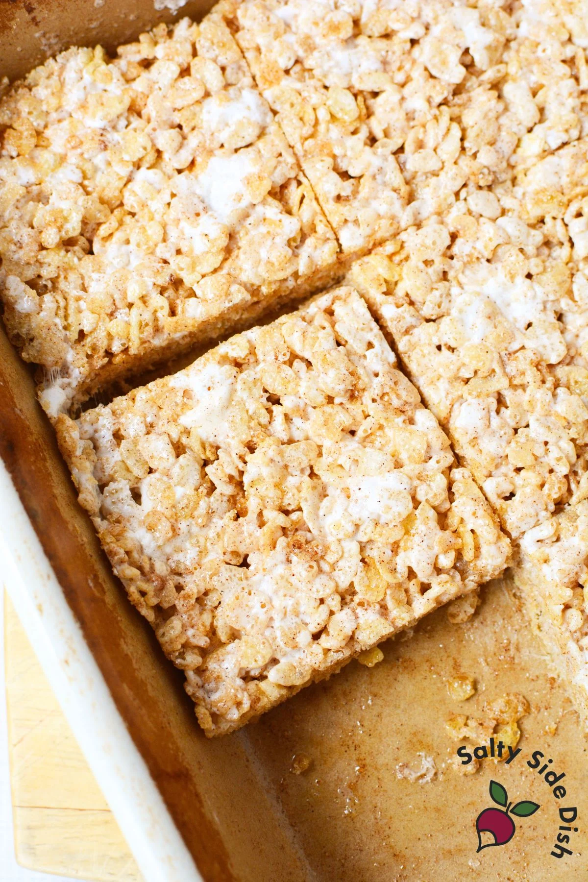 Cut Texas Roadhouse Rice Krispie Treats in baking dish with cinnamon sugar and melted marshmallow topping