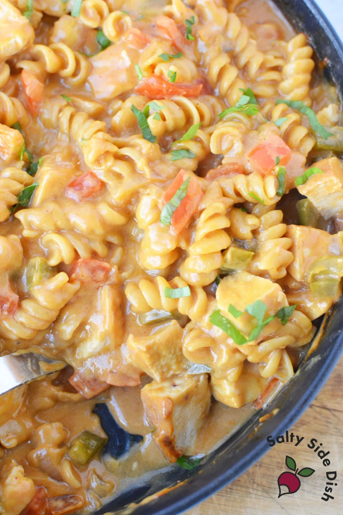 Overhead close up of fajita pasta dinner with chicken, peppers, and melted cheese in a skillet