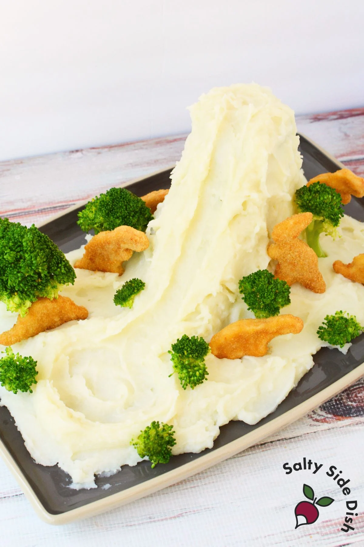 Mashed potato volcano with broccoli trees and dino nuggets pressed into the potatoes before adding gravy