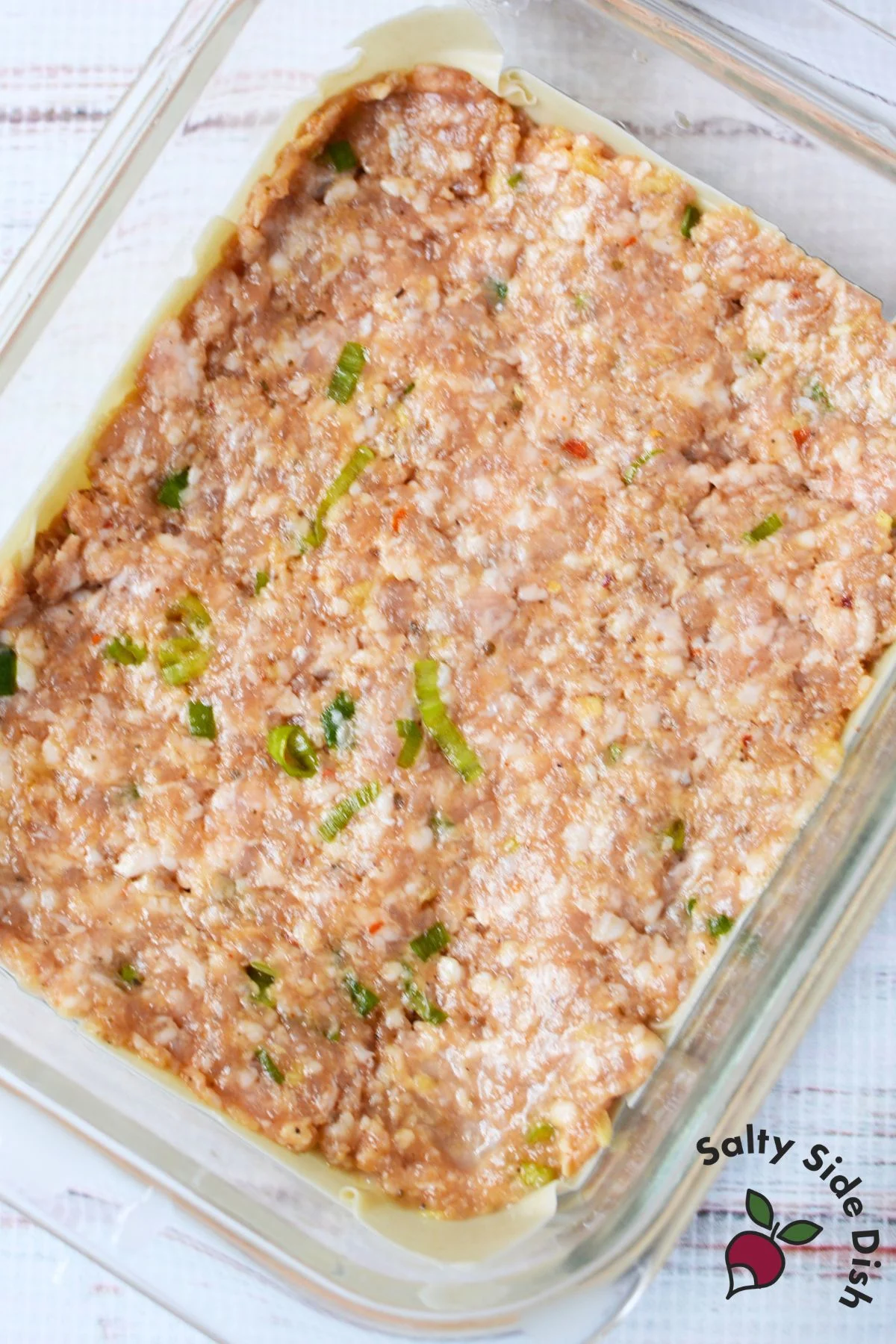 Seasoned ground pork filling spread over wonton wrappers for dumpling lasagna.
