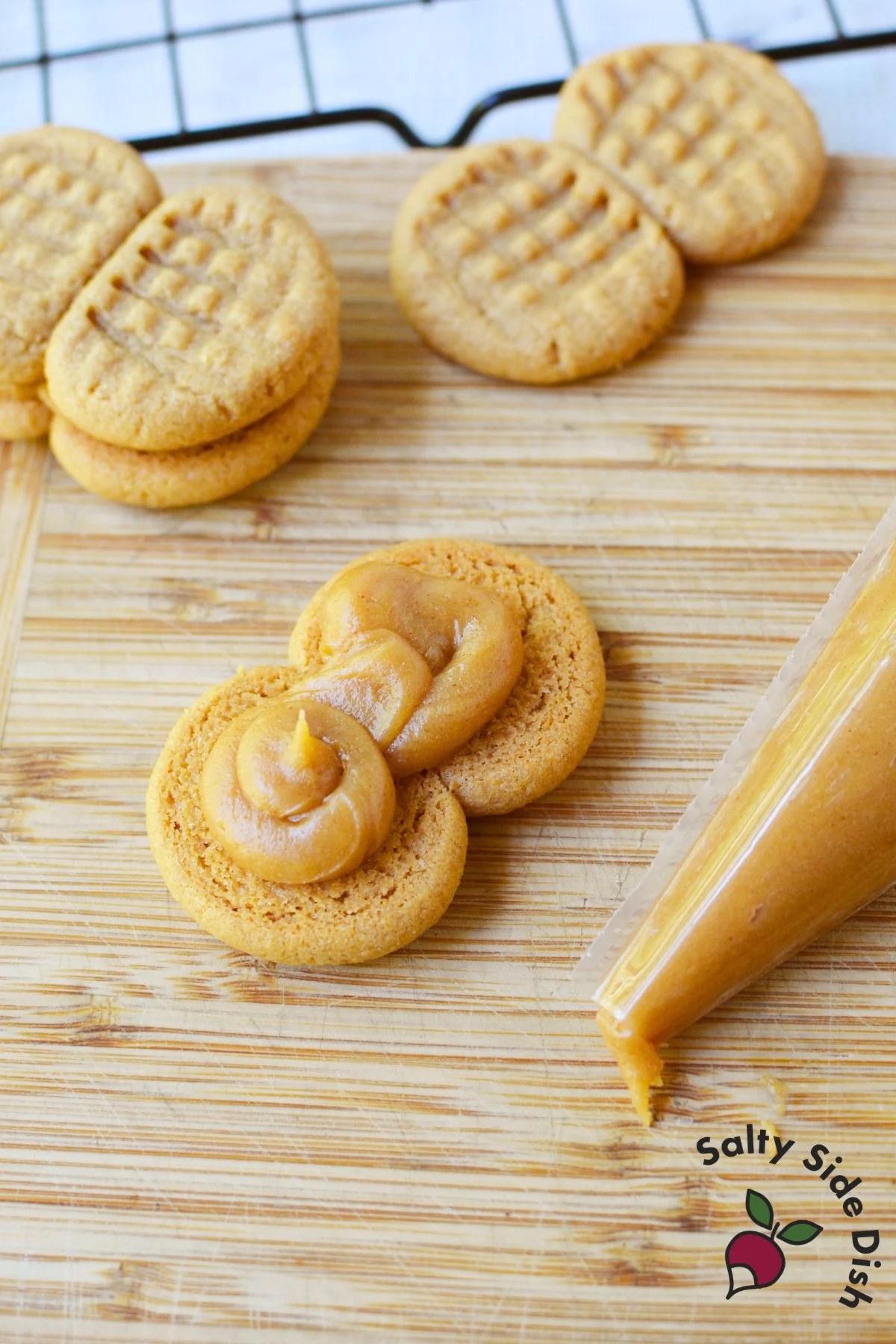 Piping peanut butter filling onto a cookie to assemble homemade Nutter Butters