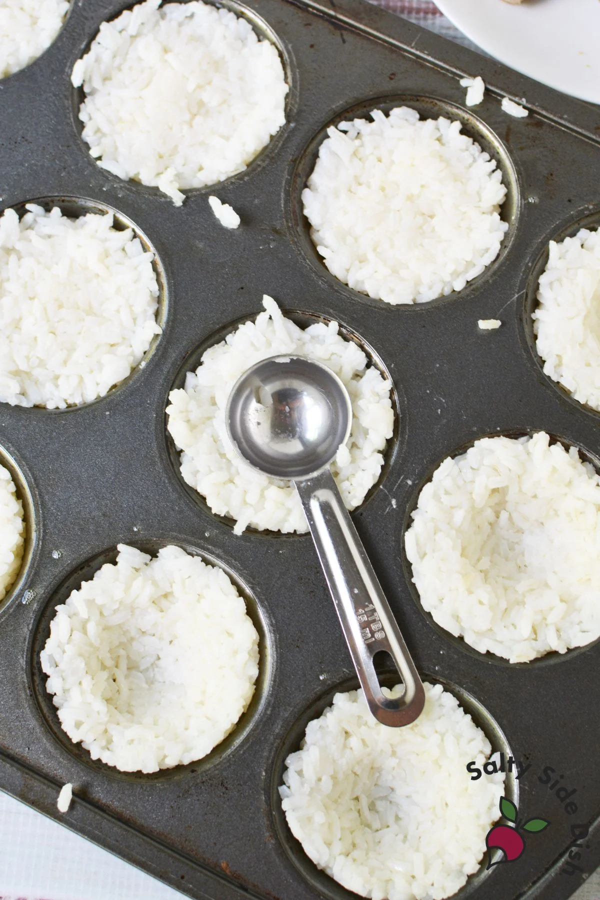 Rice pressed into a muffin tin with a portion scoop
