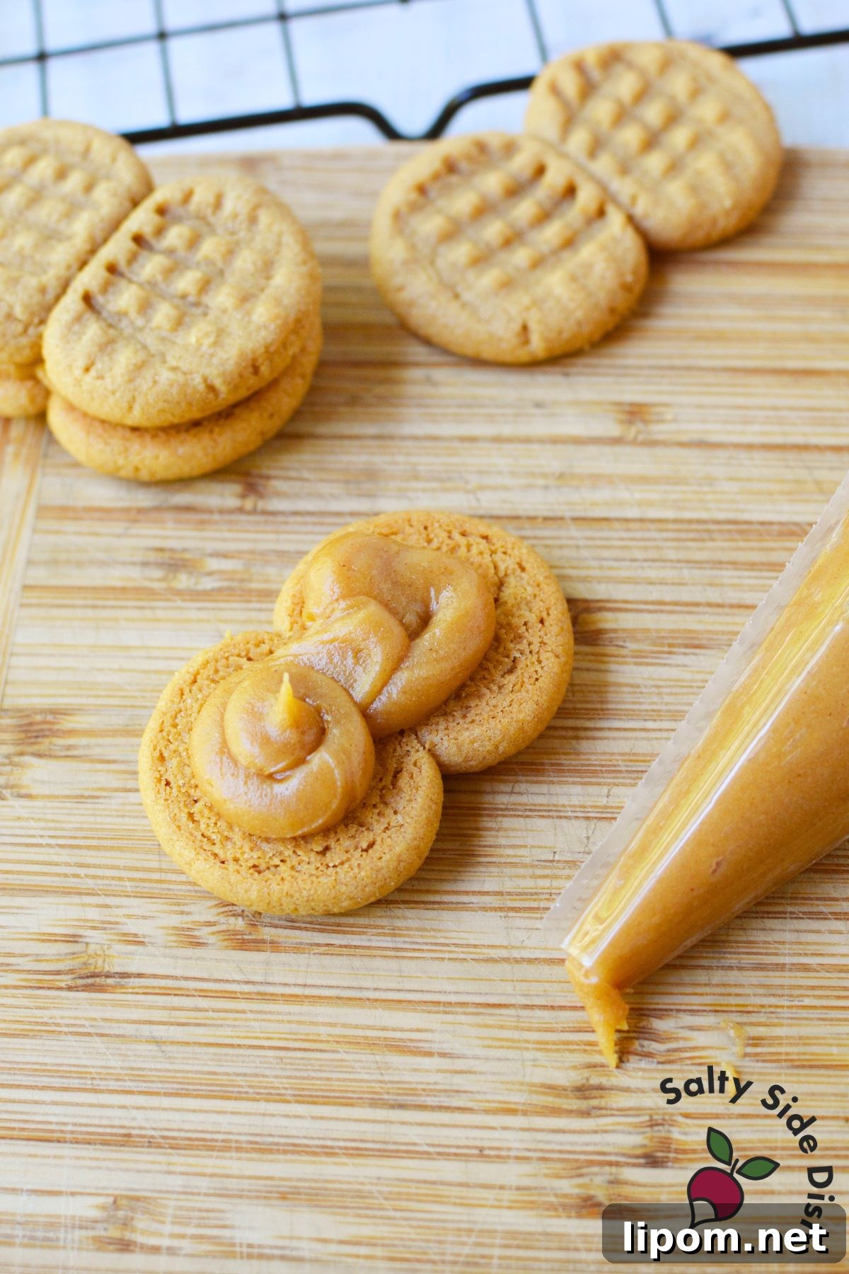 Copycat Nutter Butter Peanut Butter Cookies 6 Piping peanut butter filling onto a cookie to assemble homemade Nutter Butters