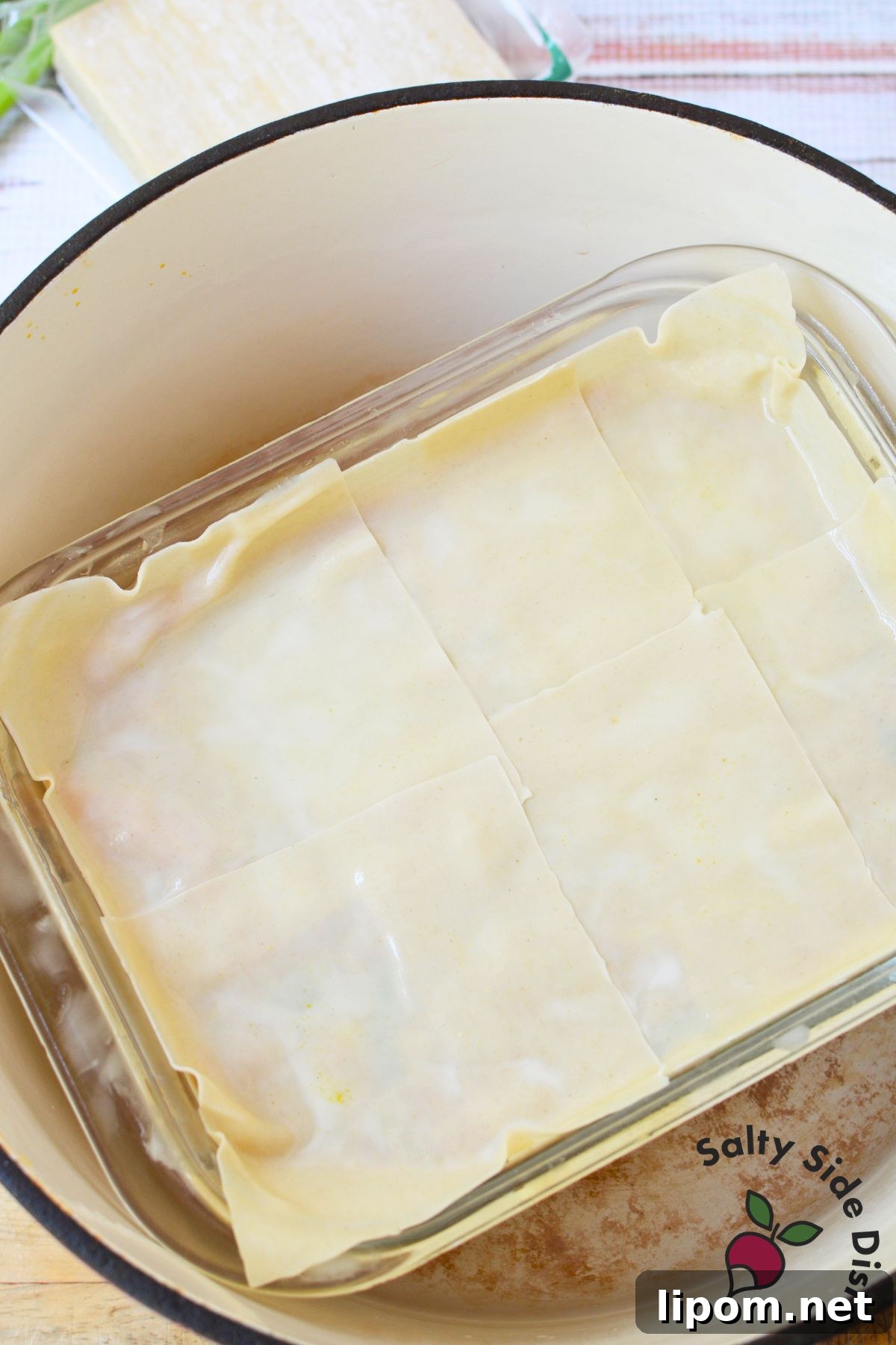 Cheesy Dumpling Lasagna Casserole with Pork and Scallions 4 Glass baking dish filled with layered wonton wrappers set inside a large pot for steaming.