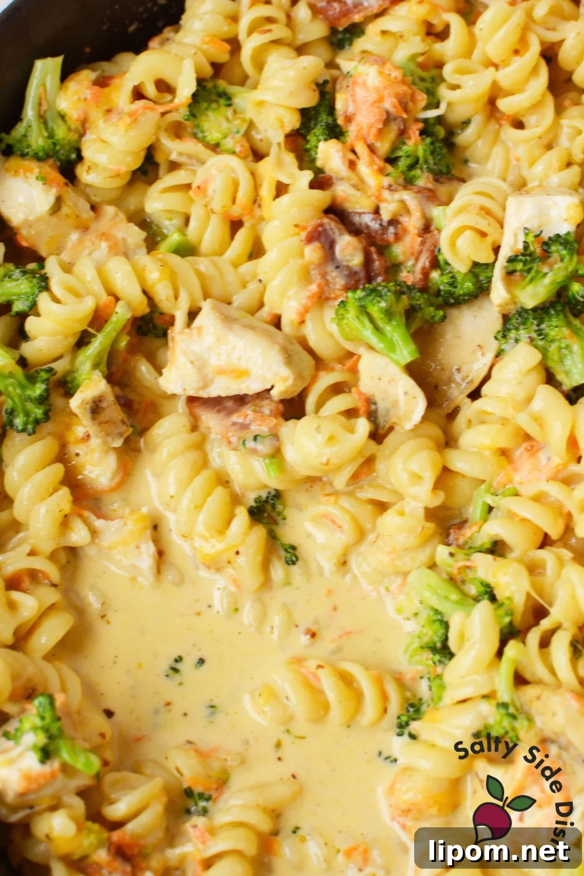 Creamy Chicken, Bacon and Broccoli Pasta with Cheese 5 Creamy chicken bacon pasta with broccoli and carrots simmering in a cheesy sauce.