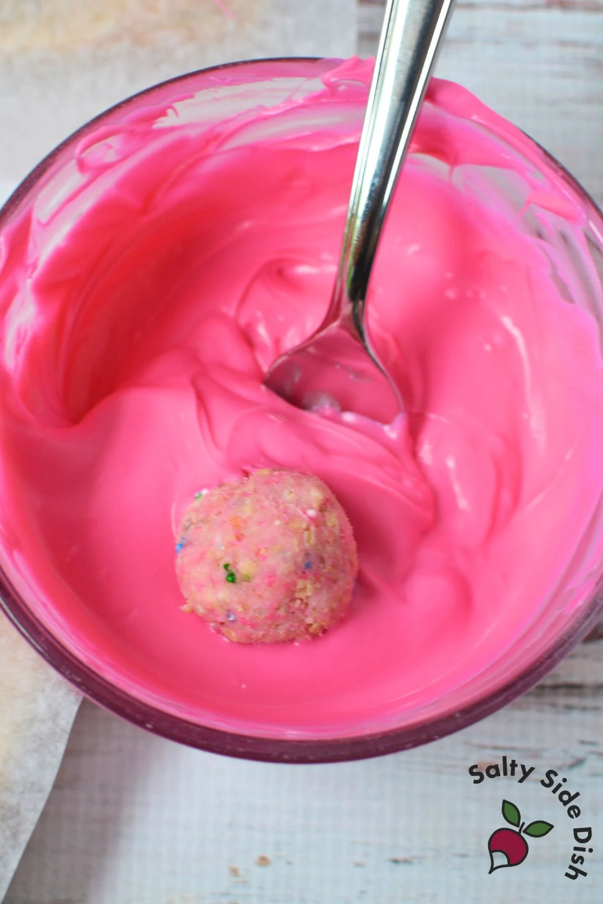 Circus Animal Cookie truffle being dipped into melted pink candy coating