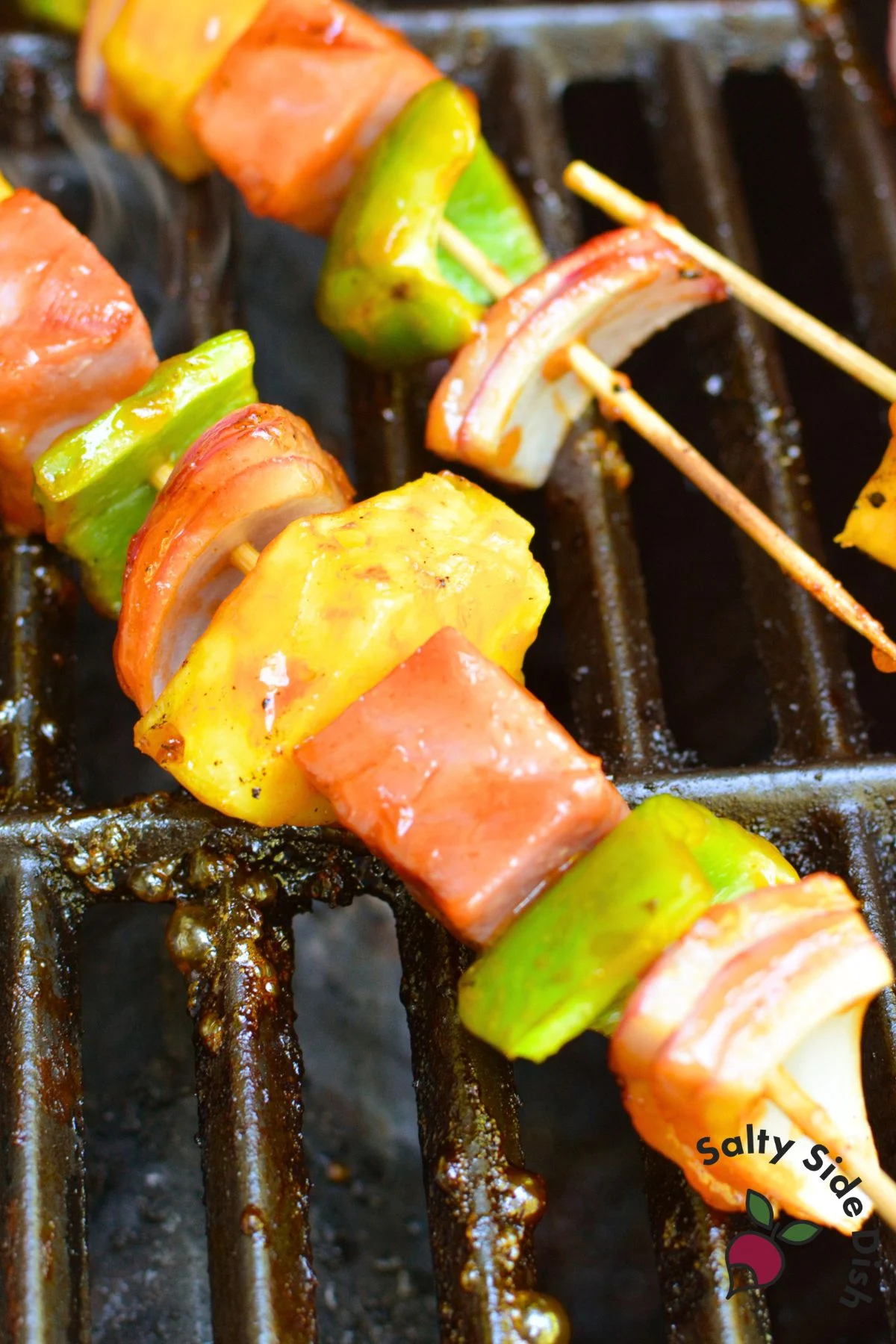 Ham and pineapple skewers grilling with green pepper and red onion