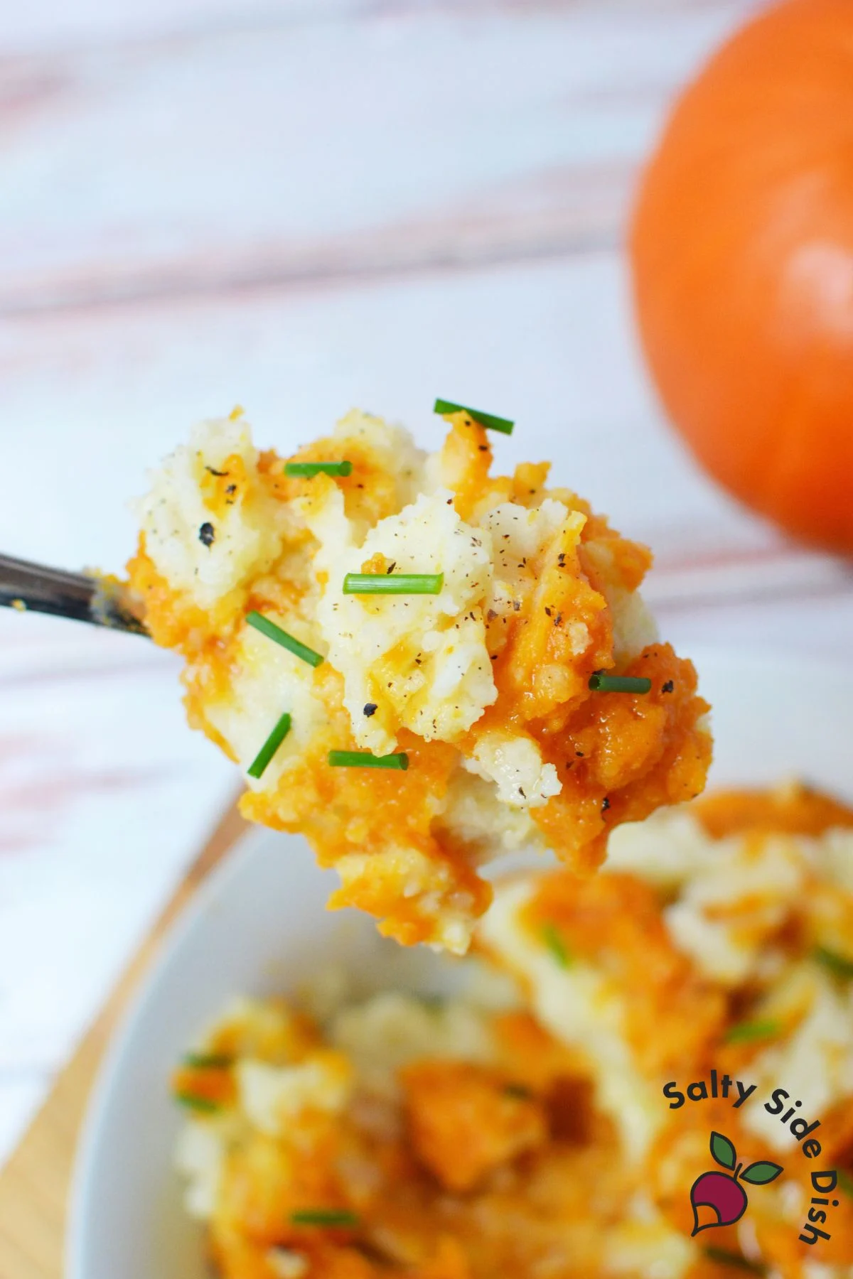 Forkful of pumpkin mashed potatoes with chives and black pepper