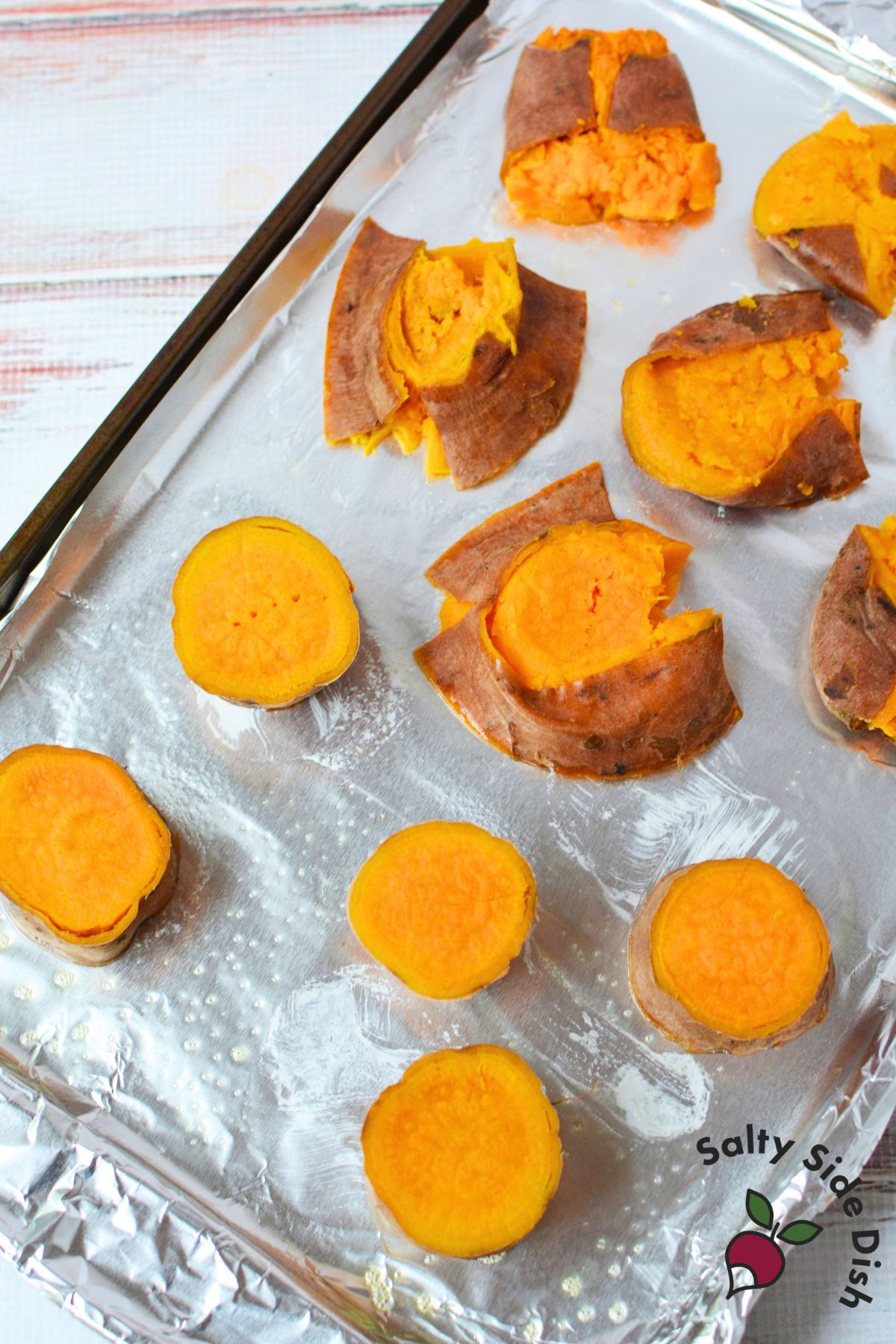 Boiled sweet potato rounds on a baking sheet before smashing and roasting