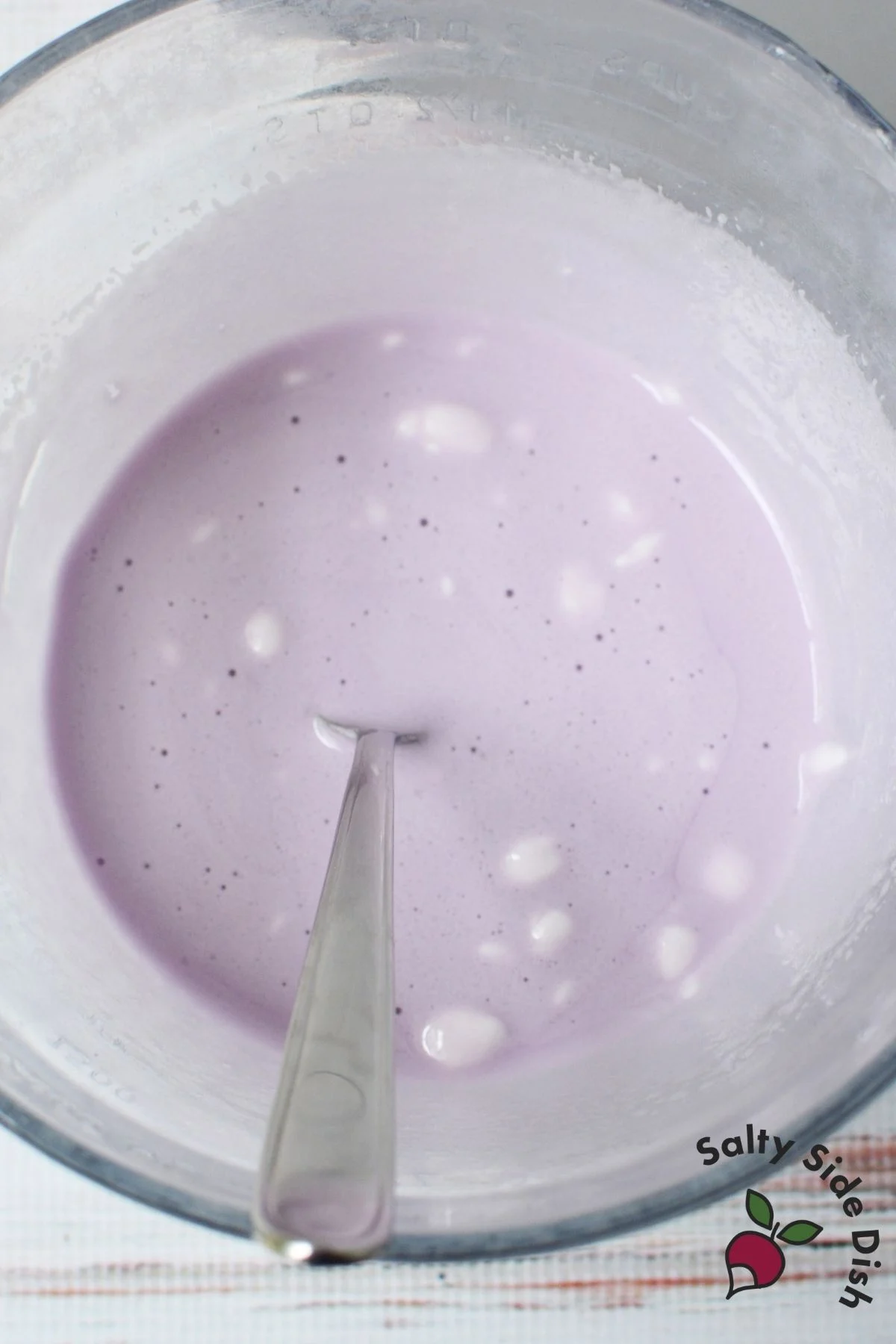 Melted marshmallow and grape Jello mixture stirred together in a mixing bowl