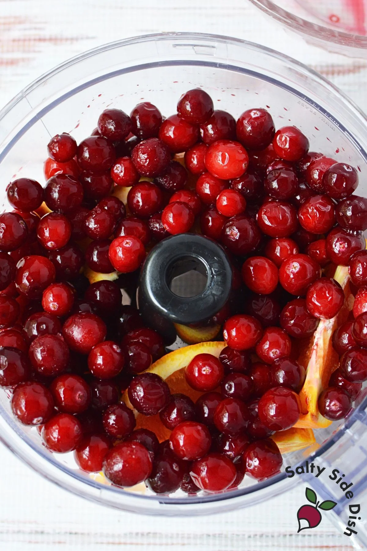 Fresh cranberries and orange wedges in a food processor for cranberry orange relish