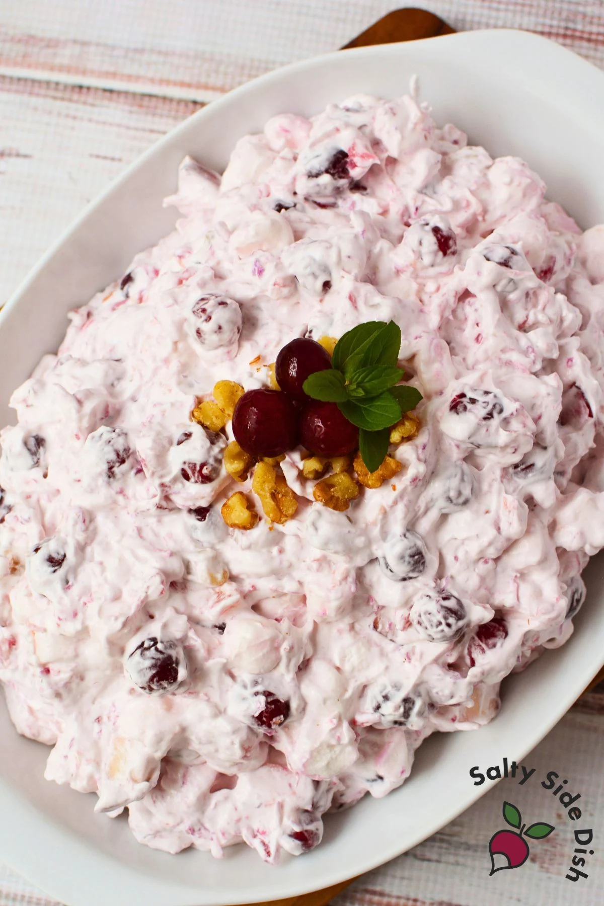 Cranberry salad on a white serving platter garnished with cranberries, walnuts, and mint leaves.