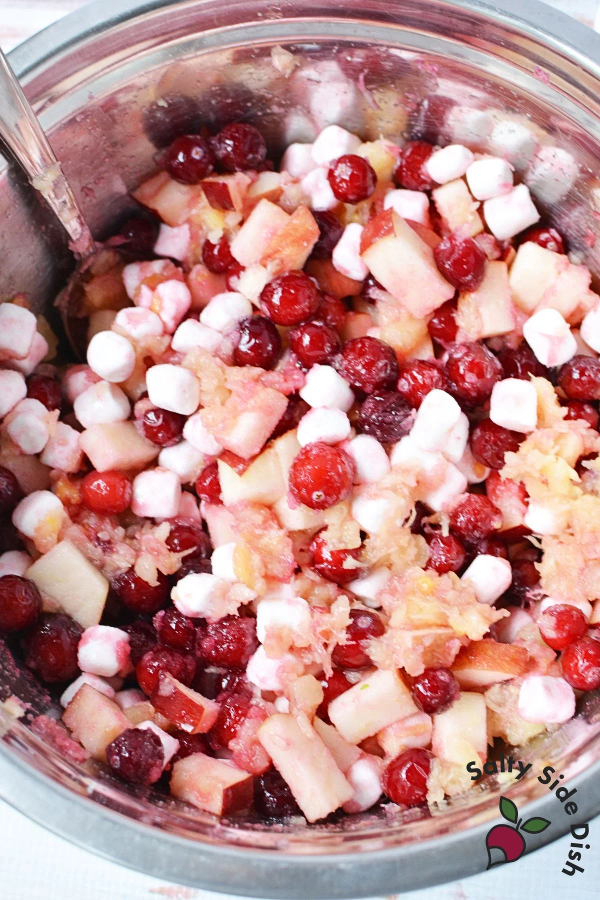 Whole cranberries, apple pieces, crushed pineapple, and mini marshmallows mixed in a stainless steel bowl.